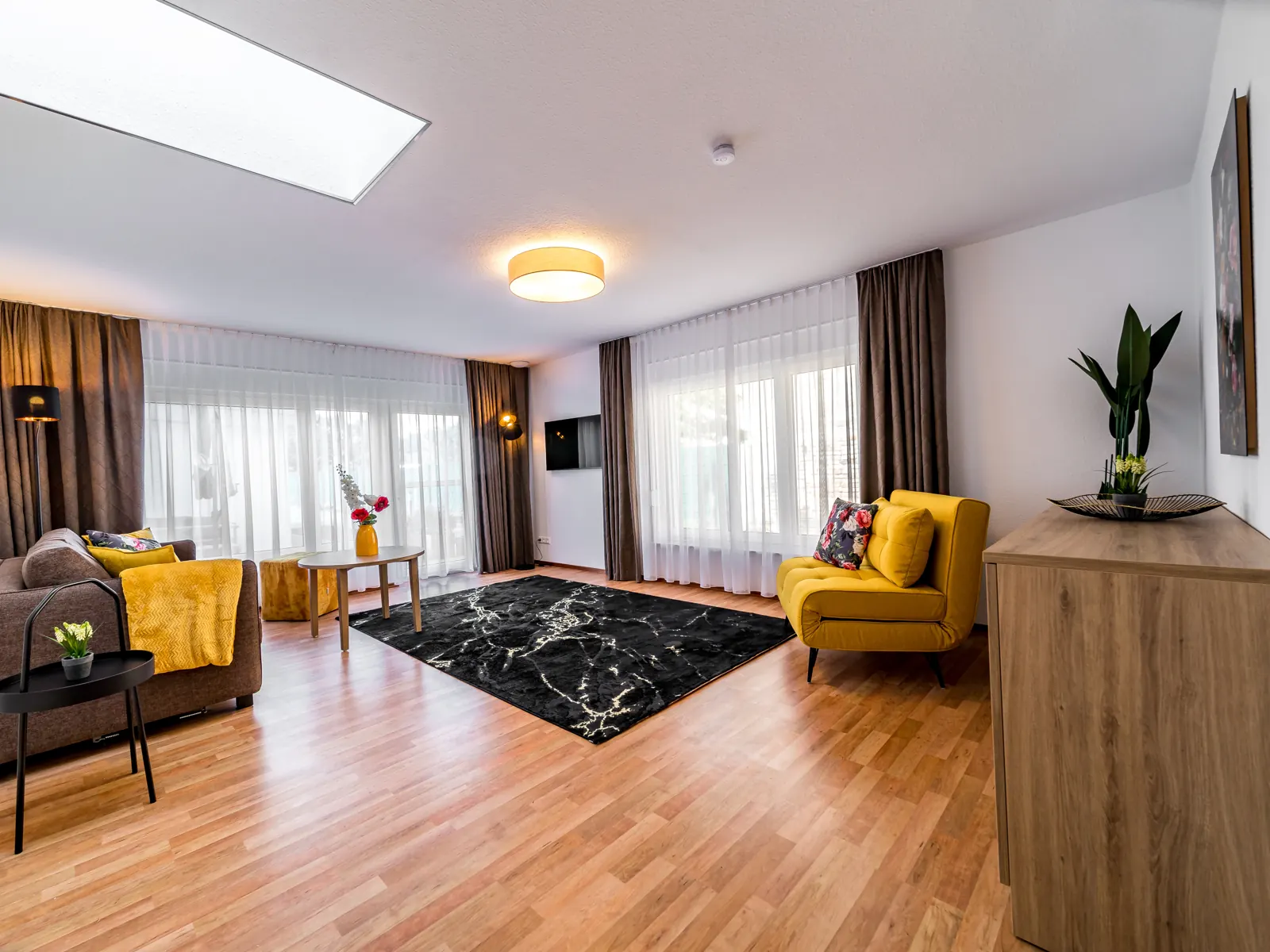 Living room of the Fontane Bungalow with sofa, yellow armchair and view to the terrace