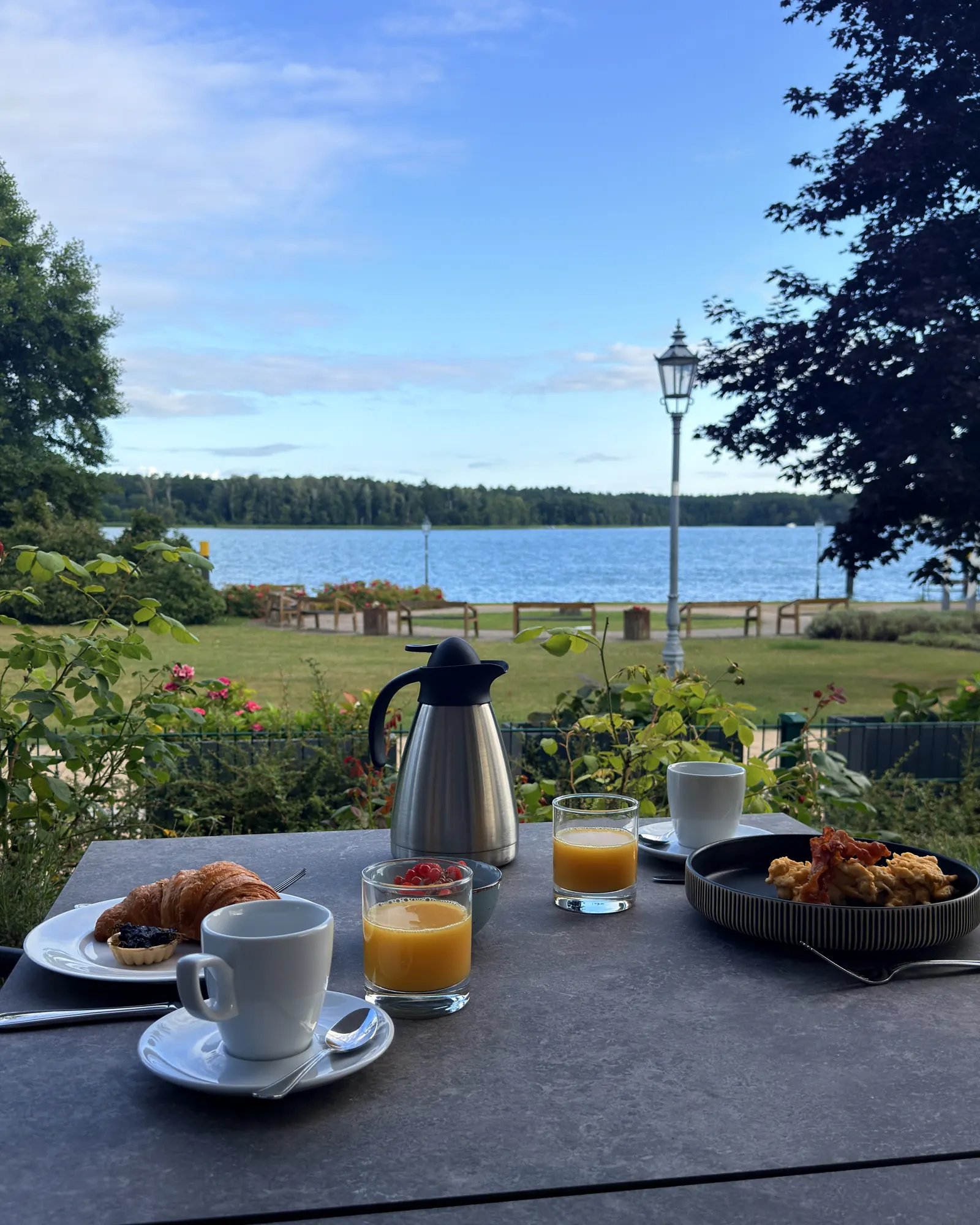 Frühstück auf der Theodors-Terrasse: Kaffee, Saft und Croissant, dahinter der Werbellinsee