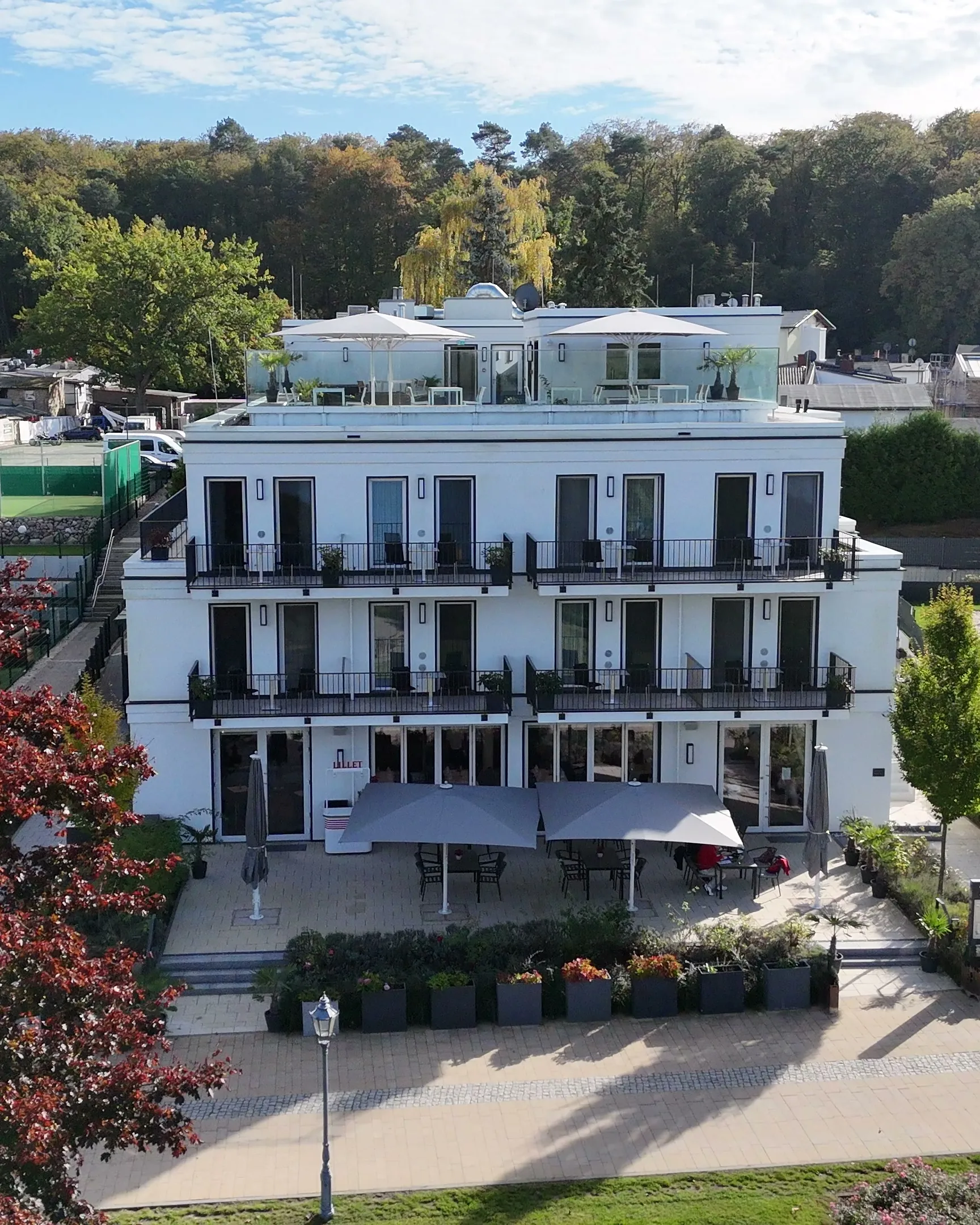Luftbild des Fontane Hotels von vorn, mit Wiese, alten Bäumen und dem Spielplatz neben dem Haus