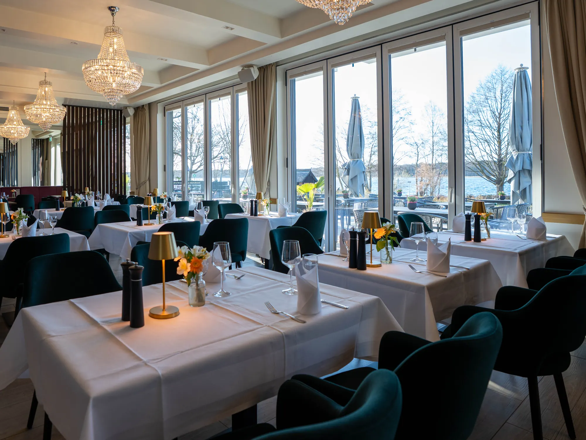 Speisesaal des Theodors Restaurants mit Kronleuchtern, gedeckten Tischen und Blick auf den Werbellinsee